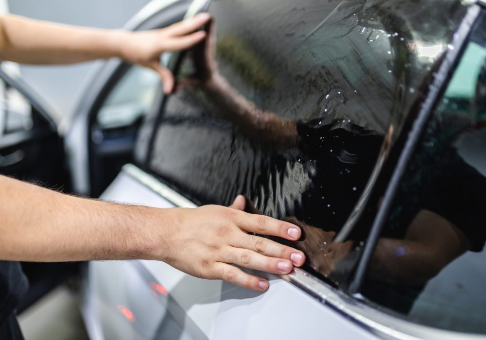 Car tinting - Worker applying tinting foil on car window.